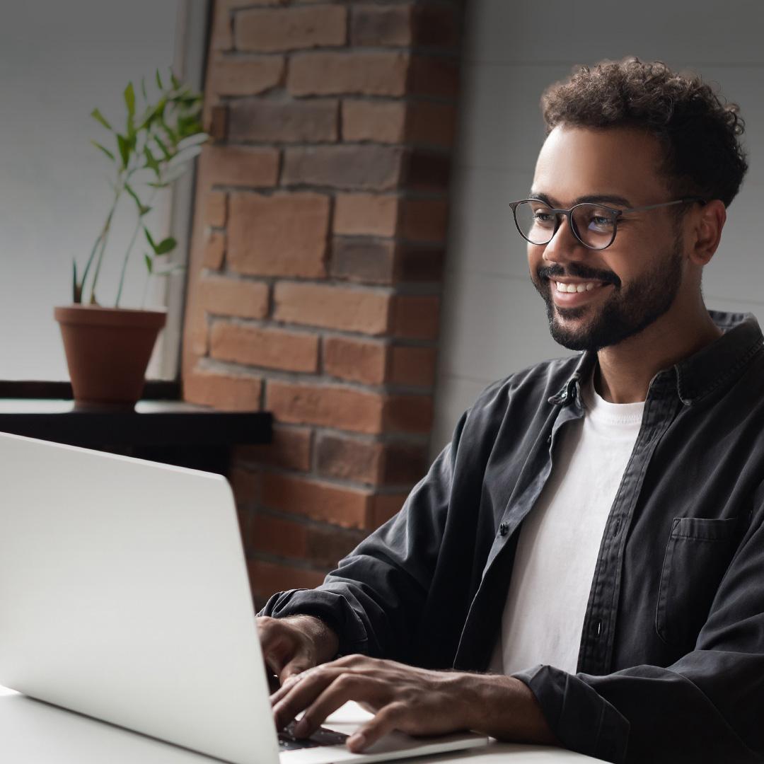 Professional smiling in front of a computer while taking an online course