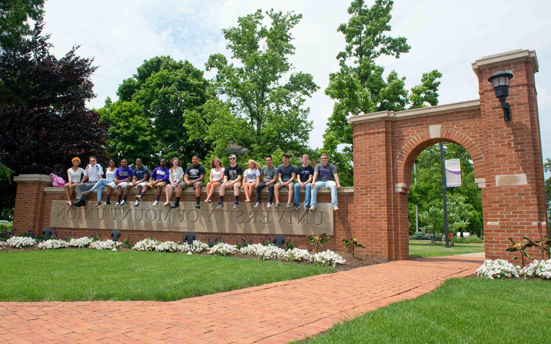 Mount Union students sitting on top of Mount Union gateway.